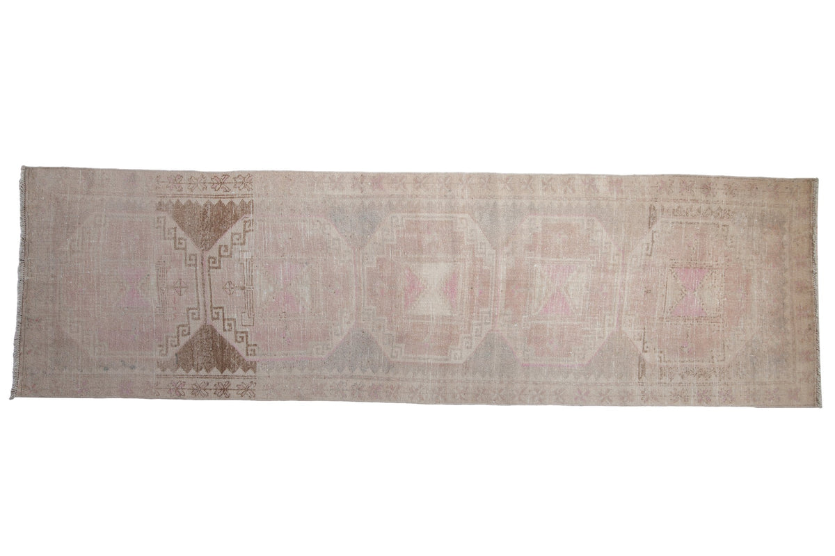 Vintage distressed Oushak runner with oversized geometric medallions in faded pink, beige, and chocolate.