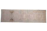 Vintage distressed Oushak runner with oversized geometric medallions in faded pink, beige, and chocolate.