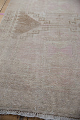 Close-up of the distressed Oushak's low pile with even wear down to the knot heads.