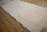 Long angled view of a distressed Oushak runner showing its soft, even wear and faded pattern.