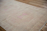 Even wear across the low pile of a distressed Oushak runner, highlighting its soft texture and faded pink motifs.