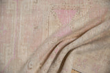 A soft fold reveals the hand-knotted texture and even wear of a distressed Oushak rug.