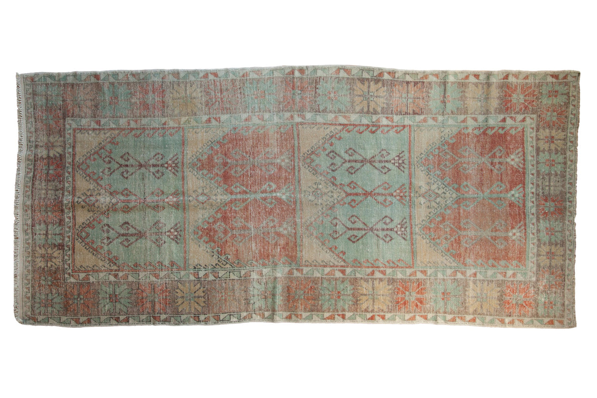 Distressed vintage Oushak runner with geometric panels in alternating soft green and burnt orange red.