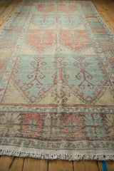The low pile and distressed texture of a vintage Oushak runner with repeating panels.