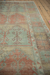 Angled perspective on the distressed Oushak runner's low pile and repeating tree of life motifs.