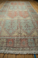 Low angle perspective of a distressed Oushak runner's faded texture and repeating geometric panels.