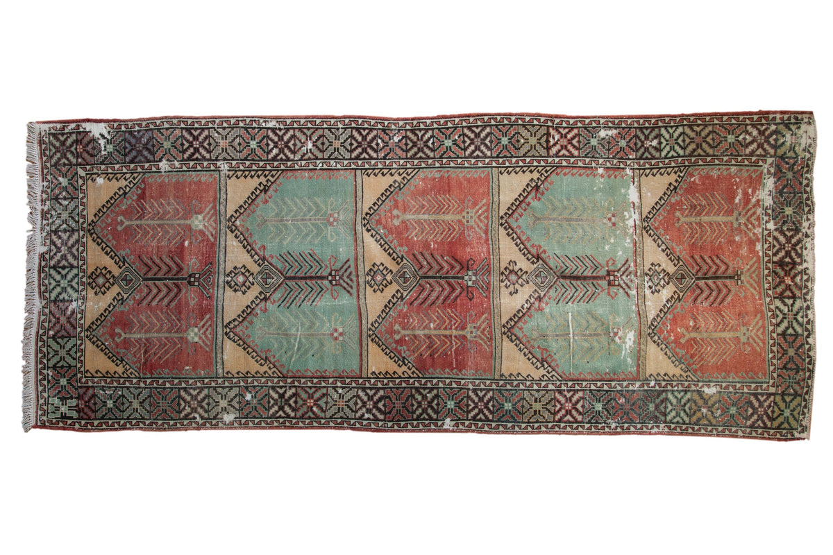 Vintage distressed Oushak runner with a tree of life design in alternating red, mint green, and gold panels.