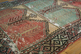 Angled detail of a distressed Oushak rug with tree of life motifs on red and mint green panels.