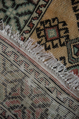 The woven foundation, knotted ivory fringe, and low-pile texture of a vintage Oushak rug.