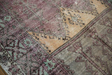 Distressed Oushak rug detail: variegated aubergine, saffron, oxidized silver, and mint green motifs.
