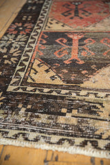 Distressed Oushak runner, showing worn pile texture and charcoal, brick red tree of life motifs.