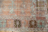 Distressed low-pile texture on a vintage Oushak's floral border in burnt orange and mint green.