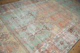 Distressed texture and visible knot heads on a vintage Oushak rug in pale green and orange.