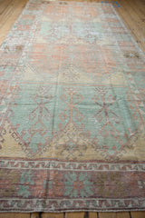 Angled perspective showing the multi-panel design and distressed texture of an Oushak runner.