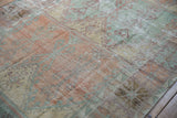 Close detail of the worn, ribbed pile on a vintage Oushak rug in muted orange and green.