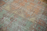Mostly even wear across the knot heads of a distressed Turkish Oushak rug in mint green and burnt orange.
