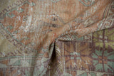 A soft fold in the distressed Oushak runner reveals its worn, hand-knotted texture.
