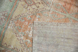 Detail of a vintage Oushak runner's corner showing the worn pile and hand-knotted back.
