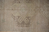 Vintage distressed Oushak runner, faded ivory and brown rams horn motifs with faint foundation.