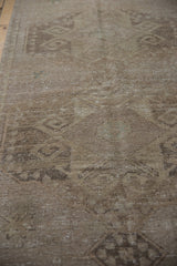 Distressed Oushak runner's worn pile texture with faded beige and charcoal patterns.