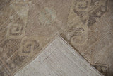 Distressed Oushak rug pile with visible foundation, revealing its hand-knotted beige reverse.