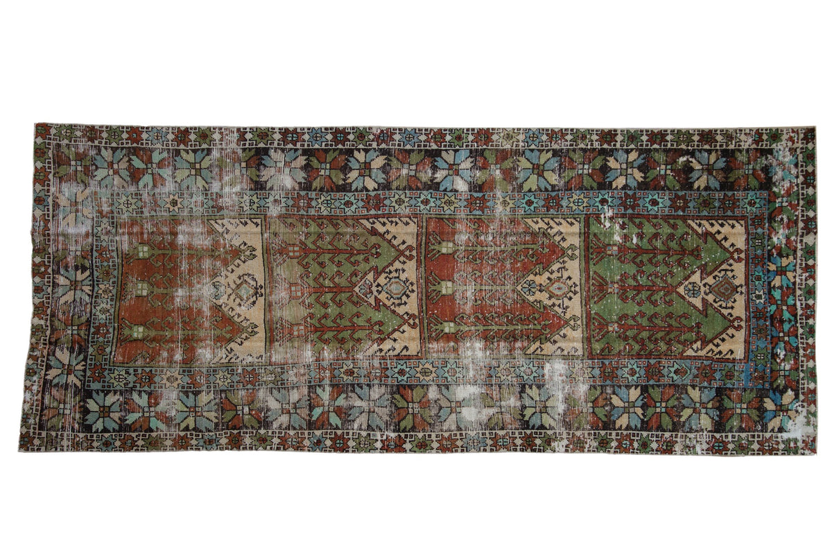 Vintage distressed Oushak rug runner with a multi-panel germinating design in rust, sage green, and ivory tones.