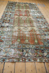 Low angle highlighting the distressed texture and geometric panels on a vintage Oushak runner.