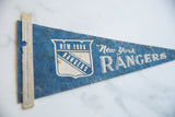 New York Rangers felt pennant with cream edge and blue shield logo.