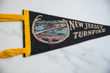 Left edge of vintage New Jersey Turnpike felt pennant, featuring yellow binding and blue bridge scene.