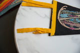 Lower graphic detail of vintage felt pennant showing bridge, blue water, and yellow binding.