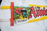 Retro graphic on a vintage felt pennant showing a covered bridge and horse-drawn carriage.