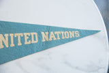 Robin's egg blue felt texture with cream 'UNITED NATIONS' lettering.