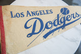 Vintage Los Angeles Dodgers felt pennant, blue 'Los' text, red binding, aged cream texture.