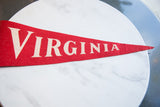 Close-up of vintage red felt Virginia pennant, highlighting textured fabric and cream lettering.