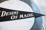 Vintage black felt pennant displaying 'Desert Of Maine' text with textured lettering.