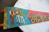 Detail of vintage Ponderosa felt pennant showing three retro cowboys and orange trim.