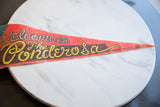 Vintage red felt Ponderosa banner, retro yellow cowboy script, and textured surface.