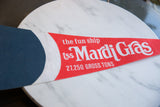 Detail of the white printed text on the red felt of the vintage Mardi Gras pennant.