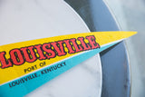 Angled close-up of the vintage felt pennant tip, showing creased yellow and blue.