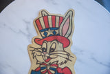 Close-up of Bugs Bunny's patriotic hat on the felt banner, detailing the aged colors and light crease.