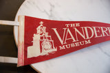 Detailed white graphic of the Vanderbilt Museum building on the red felt flag.
