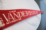 Angled close-up on the white serif text printed on the red felt pennant.