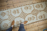 Vintage distressed Kars runner with short ivory pile texture and decorative camel motifs.
