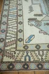 Distressed vintage Oushak rug corner showcasing light blue serrated leaf motifs and geometric borders.