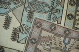 Distressed Oushak rug corner detail, highlighting geometric floral border in mauve and powder blue.