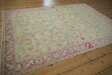 Angled perspective of a vintage Sparta rug with a lime green field and dusty pink floral border.