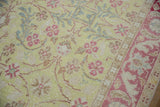 A distressed Sparta rug's textured pile with pink floral motifs, powder blue leaves, and visible even wear.