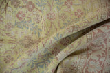 The soft, pliable texture of a distressed vintage rug with a lime green and dusty pink floral pattern.