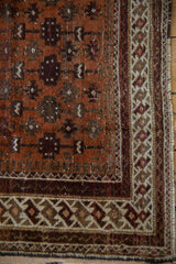 Vintage Afghani Belouch rug corner detail: rust and ivory geometric border, textured gul field.