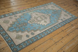 Distressed Oushak runner texture with sky blue serrated medallion and pale dusty mauve checkered motifs.